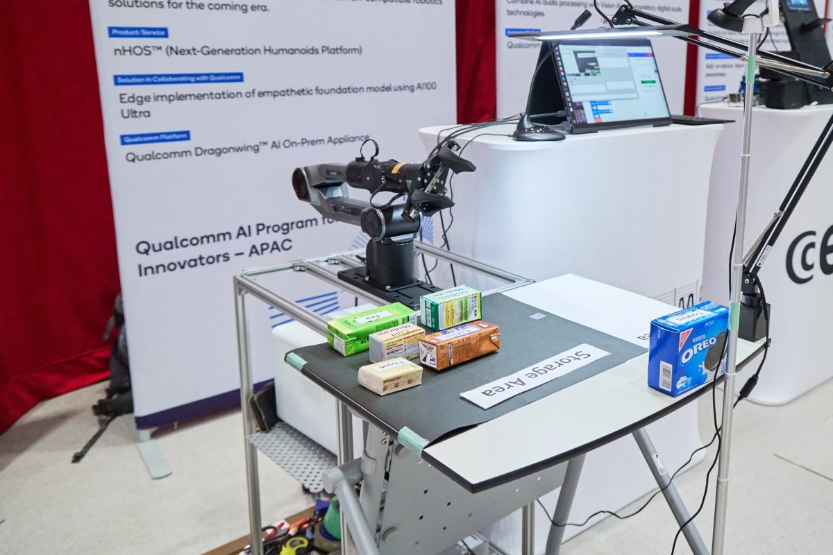 ロボットアームが複数のパッケージ商品（茶、薬、ティッシュ、コーヒー、オレオ）を操作しており、次世代ヒューマノイドプラットフォームやエッジAI技術が示されている。