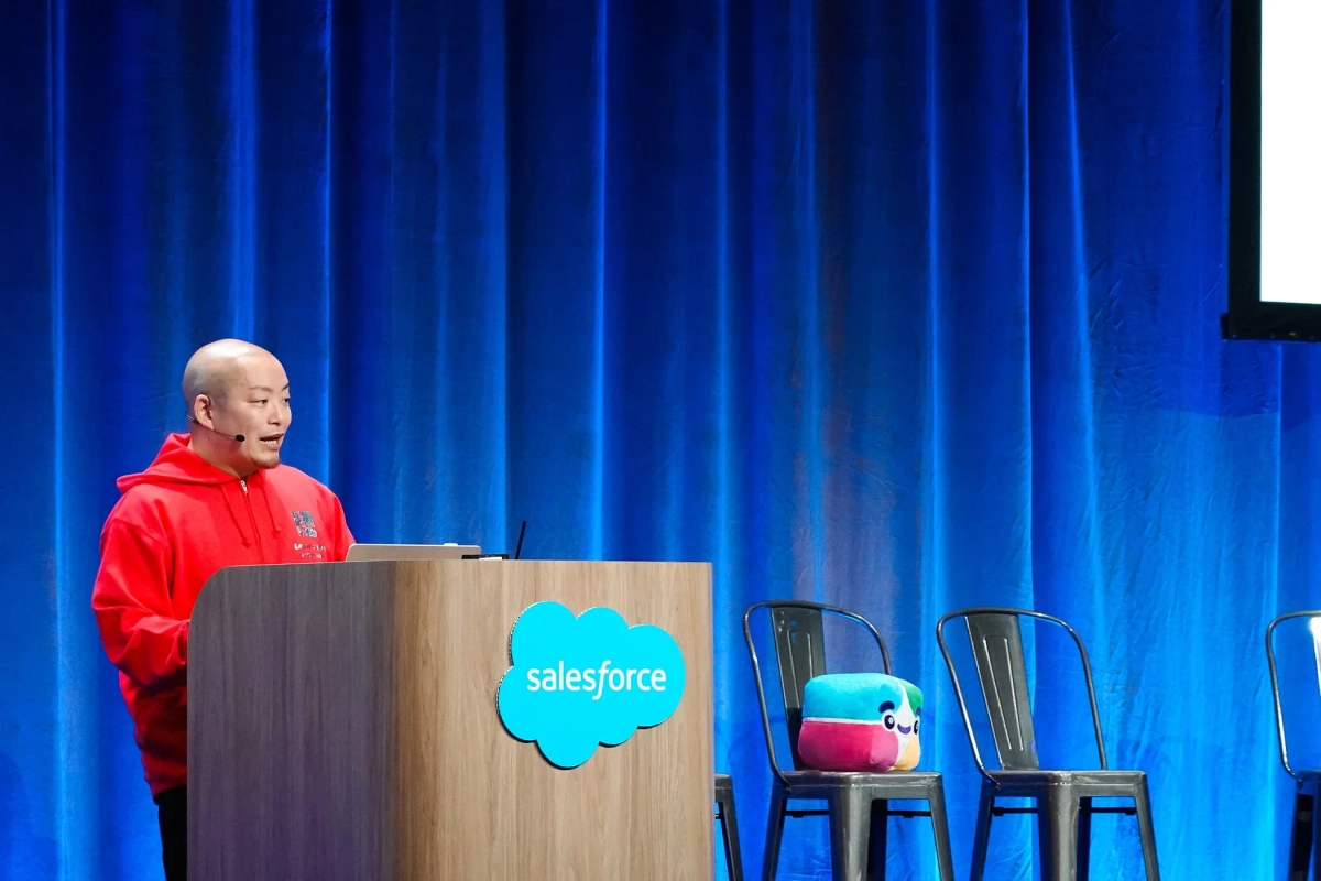 青いカーテンを背景にプレゼンテーションを行う平塚武氏と、隣の椅子に置かれたカラフルなぬいぐるみ