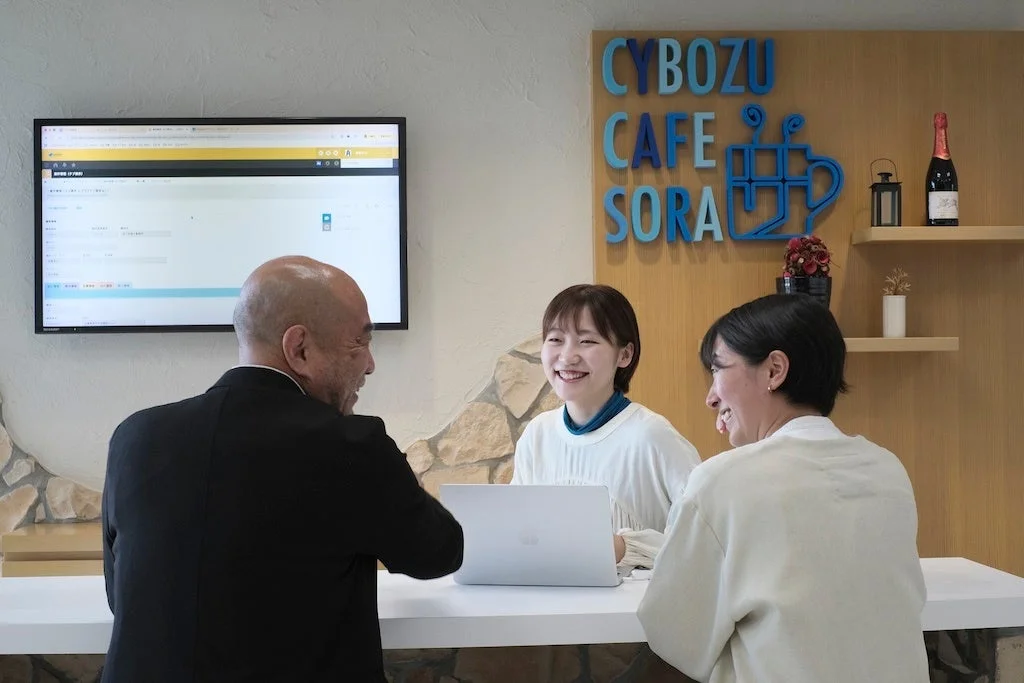 サイボウズカフェSORAでラップトップを囲んで笑顔で会話する人たち