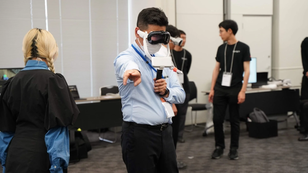 VRヘッドセットを装着した男性がデバイスを操作しながら前方へ指をさしている様子