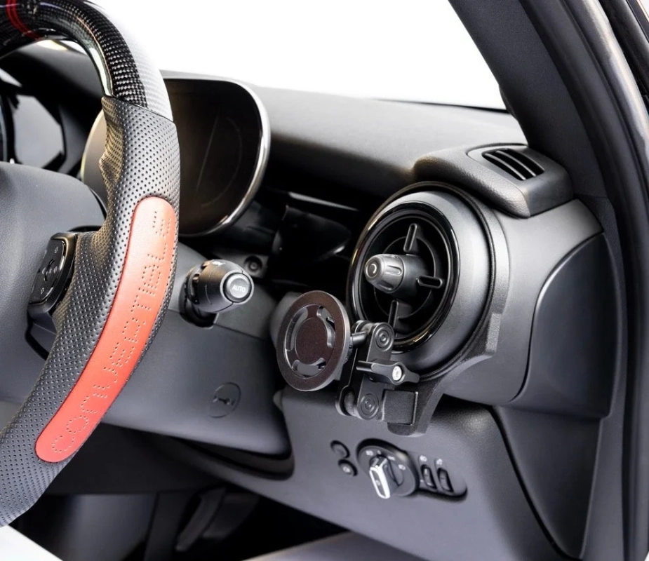 車の運転席からの視点で、ステアリングホイール、ダッシュボード、エアコン吹き出し口、スマートフォンホルダーが写っています。